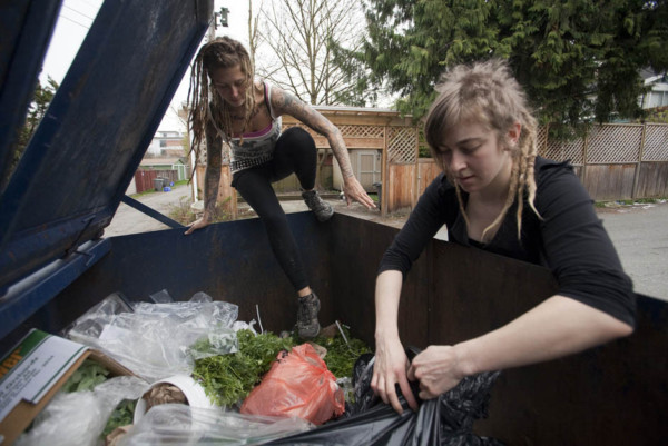 May Wollf, 28, climbs into a dumpster while Robin Pickell tears open a garbage bag in an alley behind Commercial Drive in Vancouver, British Columbia April 10, 2012.